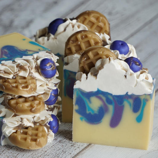 Decorative soap bars with waffle and blueberry toppings on a wooden surface