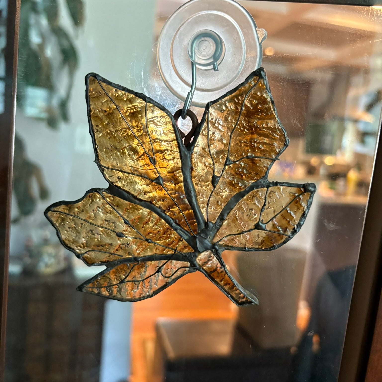 Decorative leaf-shaped object on a glass surface with a blurred indoor background