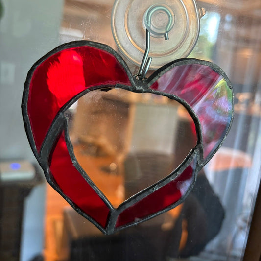 Heart-shaped red stained glass hanging on a mirror
