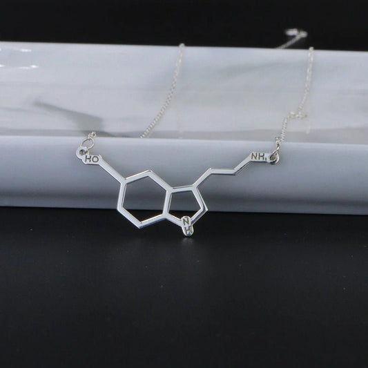 Silver molecular structure necklace on a white marble surface with a black background